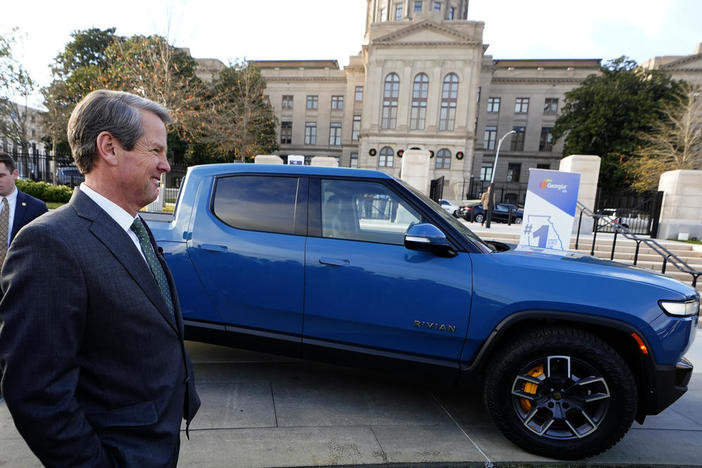 Gov. Brian Kemp smiles as he stands next to a Rivian electric truck during a ceremony to announce that the electric truck maker plans to build a $5 billion battery and assembly plant east of Atlanta projected to employ 7,500 workers, Thursday, Dec. 16, 2021, in Atlanta.