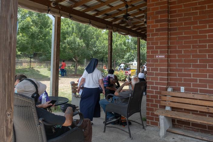 People seek relief in the shade outside the Daybreak Day Resource Center in Macon during snack time as temperatures in central Georgia reach close to 100 degrees.