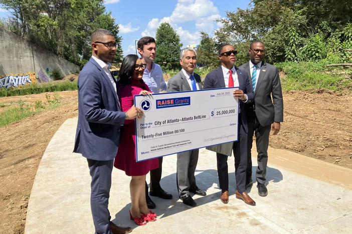 On hand for a giant $25 million federal Rebuilding American Infrastructure with Sustainability and Equity (RAISE) check presentation ceremony on a future segment of the Northeast Trail on July 24 are, from left, Christopher Coes, U.S. Assistant Secretary for Transportation Policy, U.S. Department of Transportation; U.S. Rep. Nikema Williams; U.S. Sen Jon Ossoff; Atlanta City Councilmember Alex Wan, Clyde Higgs, president and CEO of Atlanta BeltLine. Inc.; and Solomon Caviness, commissioner of the Atlanta De