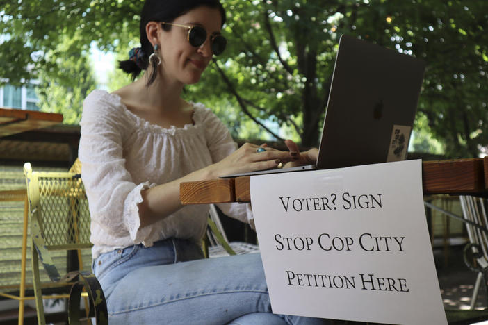Activist Hannah Riley works on her laptop at Muchacho, a local taco restaurant, while gathering signatures from fellow voters, in Atlanta, Thursday, July 13, 2023. Organizers are trying to force a referendum that would allow voters to decide the fate of a proposed police and training center, but attorneys for the city say the petition drive is invalid. 