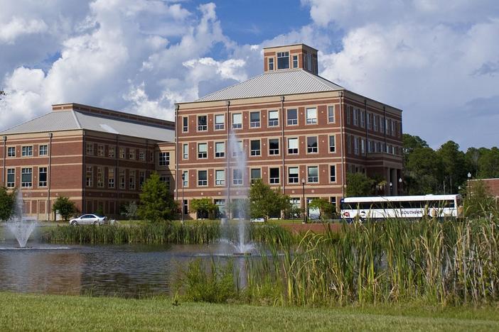 Georgia Southern University's main campus in Statesboro, with two academic buildings in the background and a pond with fountains and tallgrass in the background.