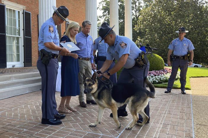 Police K-9 Rex struggles with his handler Trooper First Class Gustabo Deanda during a graduation ceremony, Thursday, July, 13, 2023, at the governor's mansion in Atlanta. Georgia first lady Marty Kemp, second from left, helped rescue Rex from an animal shelter last year and arrange for him to enter training with the Georgia Department of Public Safety. Georgia Gov. Brian Kemp, third from left, watches. 