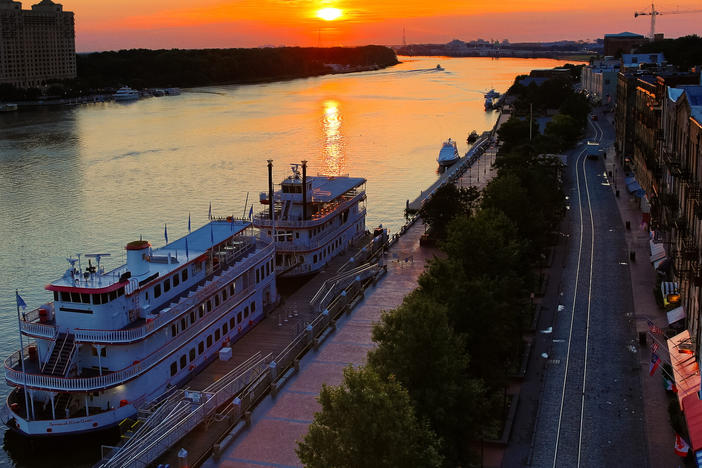 An aerial view of Savannah's River Street, with two riverboats docked along the Savannah River