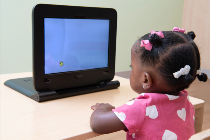 A young girl watches a screen