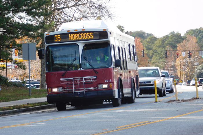 A red bus is shown traveling toward the camera.  Its sign reads "35 Norcross."