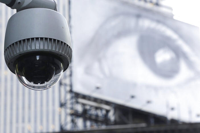 A security camera is mounted on the side of a building overlooking an intersection in midtown Manhattan, Wednesday, July 31, 2013 in New York. In the background is a billboard of a human eye.