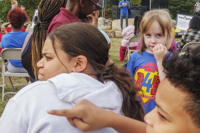 Bibb County Schools students, foreground, while Superintendent Dan Sims, background, speaks at the first of half a dozen  after school fairs held to promote school attendance.