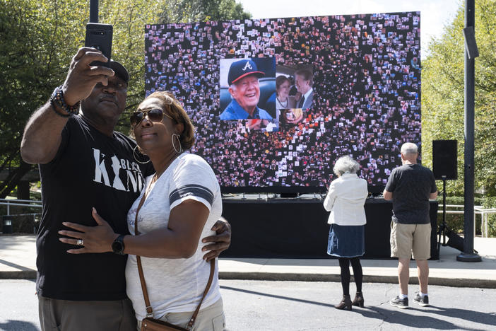 Kevin and Ursula Jones take a photo together in front of a video screen while attending the celebration for President Jimmy Carter's 99th birthday held at The Carter Center in Atlanta on Saturday, Sept. 30, 2023.