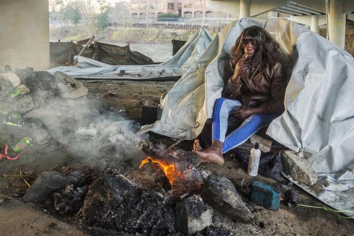  A small fire re-ignited with hand sanitizer as an accelerate warms Conta Price’s feet on a 28 degree morning in Macon in late November.