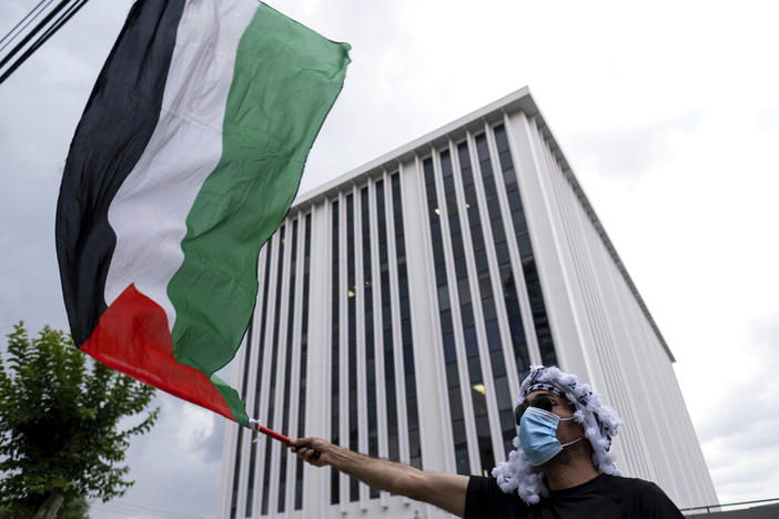 A pro-Palestinian protester waves a flag in front of the building housing the Israeli Consulate office in Atlanta on Tuesday evening, May 18, 2021. 
