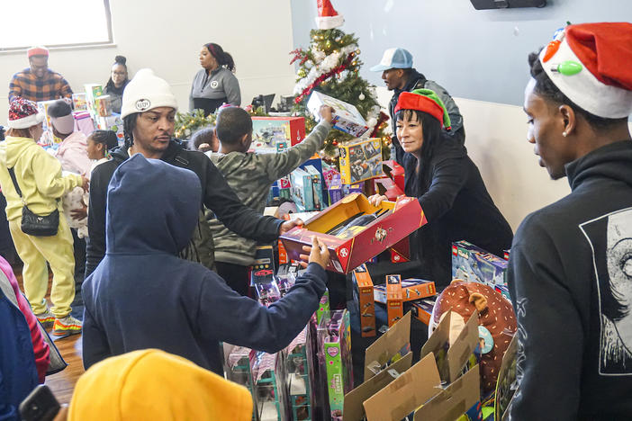 Atlanta rapper and actor Tip 'T.I.' Harris (in white cap) helps volunteers distribute holiday gifts to attendees at My Sister's House,  the women and children's shelter of the Atlanta Mission the week before Christmas 2023.