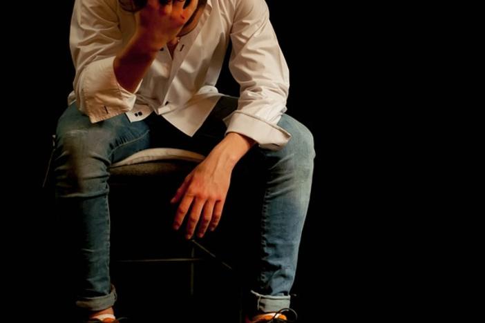 A dejected or tired teenager sits with his head in his hand