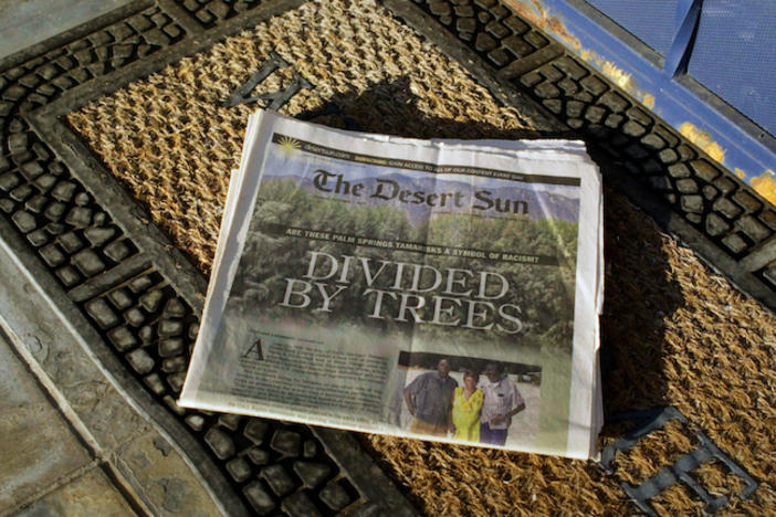 A newspaper on a welcome mat with the headline "Divided by Trees."