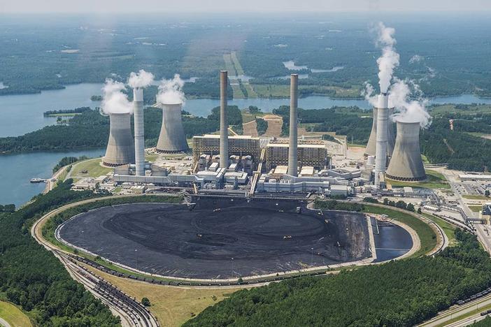 Massive trucks and front end loaders look ant sized relative to the coal piled in front of Georgia Power's Plant Scherer in this photo from 2019. 