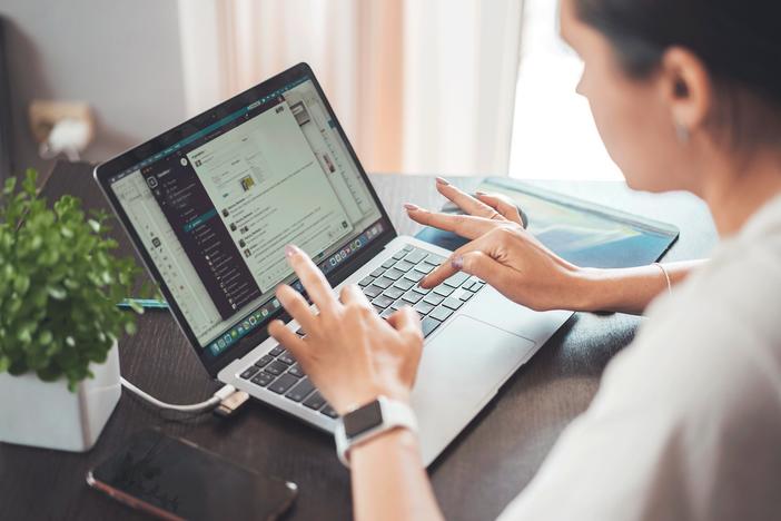A woman types on her laptop on a table at home.