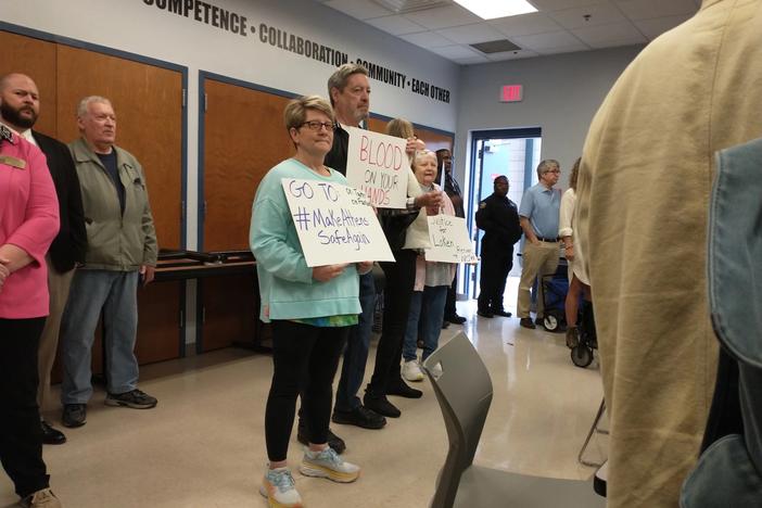 Protesters hold up signs at a press conference by Athens-Clarke County Mayor Kelly Girtz on Feb. 28, 2024.