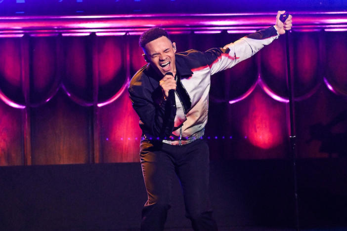 A man giving a passionate vocal perfomance on stage.