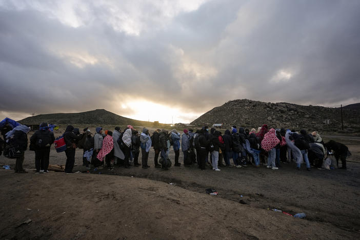 Asylum-seeking migrants line up in a makeshift, mountainous campsite to be processed after crossing the border with Mexico, Friday, Feb. 2, 2024, near Jacumba Hot Springs, Calif.  (AP Photo/Gregory Bull, File)