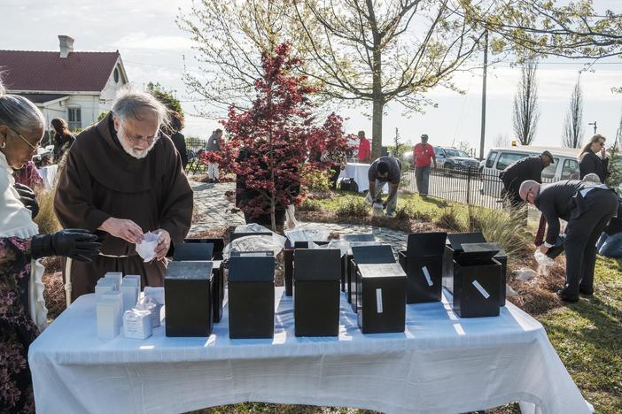 People scatter hundreds of sets of unclaimed cremated human remains around a small garden at Macon's Rose Hill Cemetery during a short ceremony Thursday. 