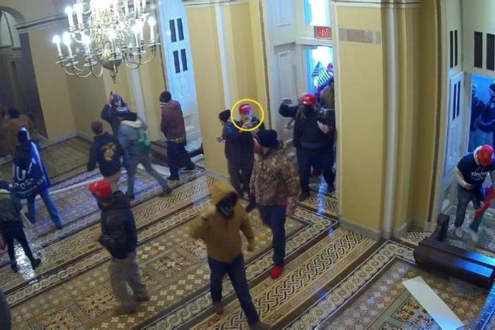 In this frame from U.S. Capitol surveillance video, the man in the yellow circle is identified by the FBI as Dominic Box, entering through the Senate wing door of the building on Jan. 6, 2021.
