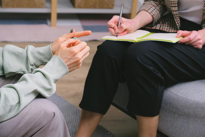 Anonymous female therapist and client sitting in armchairs during session in modern office.