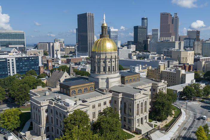 The gold dome of the Georgia Capitol gleams in the sun, Aug. 27, 2022, in front of the skyline of downtown Atlanta.