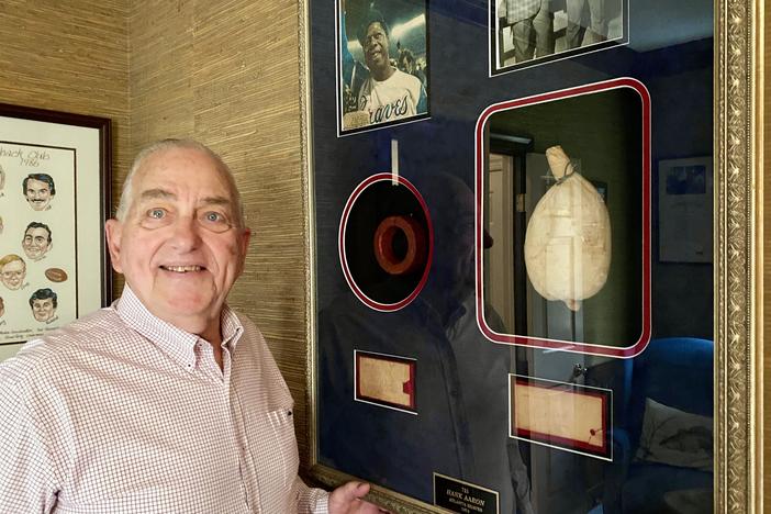 Charlie Russo, 81, poses in his Savannah home next to a framed display of the baseball batting donut and rosin bag used by Hank Aaron ahead of the slugger's record-breaking 715th home run.