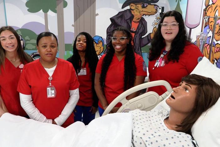 Columbus State University nursing students gather around “Victoria,” the mannequin mom that’s part of the new mother-baby simulation lab at CSU’s School of Nursing. 03/28/2024 Mike Haskey mhaskey@ledger-enquirer.com  