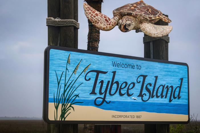 Welcome sign to Tybee Island, with a sea turtle sculpture above.