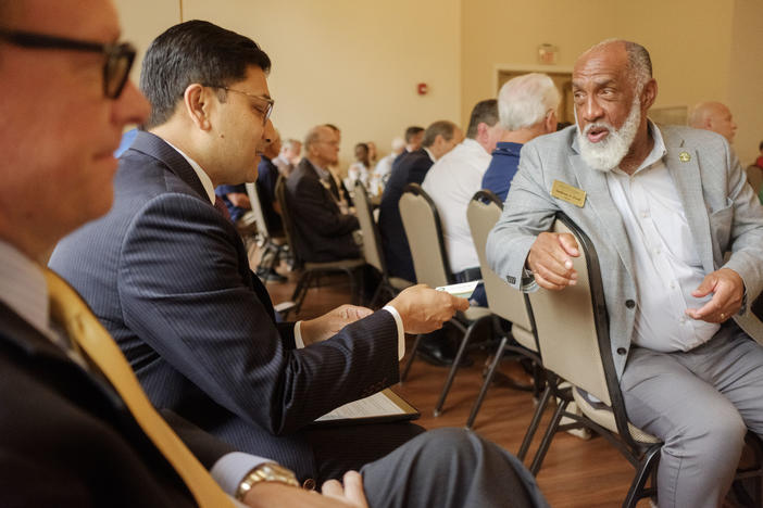 Mayor of Stockbridge Anthony Ford, right, hands off a business card to Federal Rail Administator Amit Bose before Bose spoke to the Interstate 75 Central Corridor Coalition in Indian Springs State Park. 