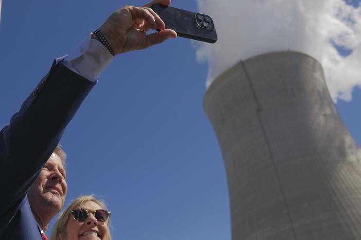 Governor Brian Kemp and Georgia First Lady Marty Kemp are shown taking a selfie in front of a nuclear cooling tower.