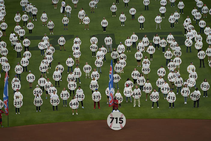 In honor of the 50th anniversary of Hank Aaron breaking Babe Ruth's home run record 715 fans match onto the field to each holding a sign to commemorate an Aaron home run before a baseball game between New York Mets and Atlanta Braves Monday, April 8, 2024, in Atlanta. Aaron passed Ruth on April 8, 1974. 