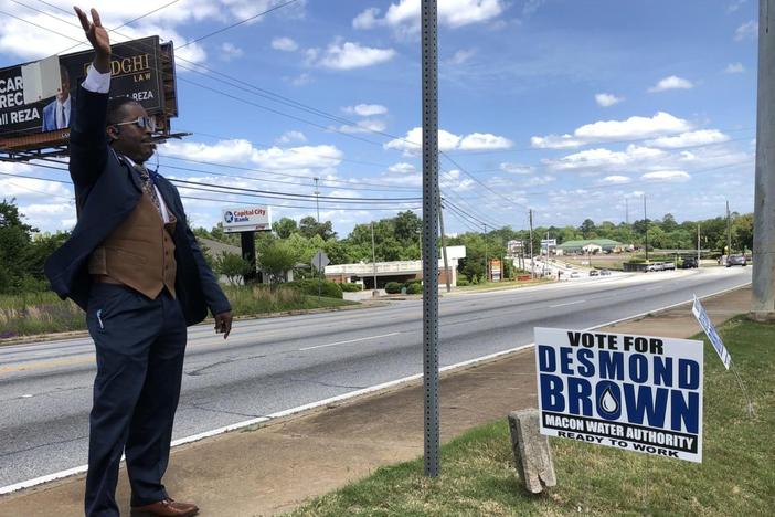 Macon Water Authority incumbent Desmond Brown waves from the sidewalk at Macon Mall where early voting is underway at the Macon-Bibb County Board of Elections. Brown said the mall’s sign prohibition infringes on his ability to campaign.