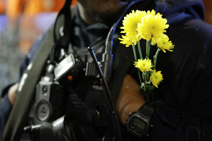 An Atlanta police officer wears flowers on his uniform during a protest over plans to build a new police training center, Thursday, March 9, 2023, in Atlanta. 