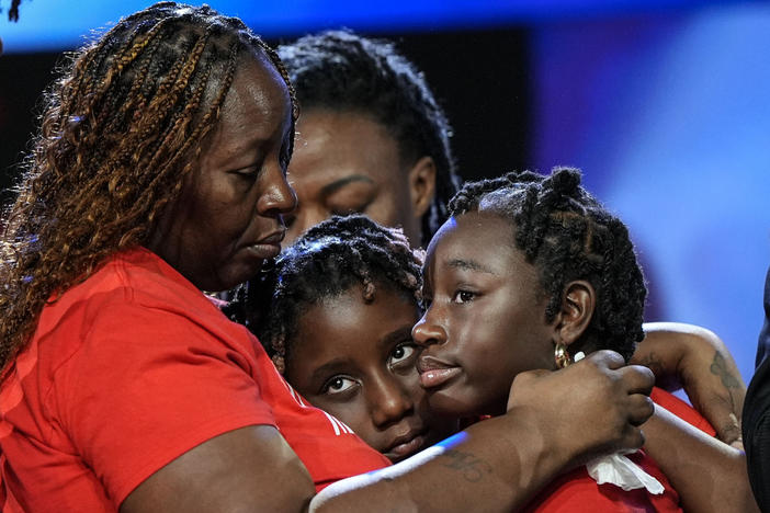 Four people, including Chantemekki Fortson, are shown in an embrace.
