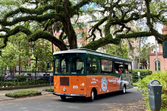 A trolley tour bus passes by Madison Square in downtown Savannah.