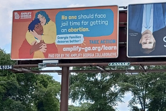 A photo of a billboard with cartoon people hugging and text that says "no one should face jail time for getting an abortion"