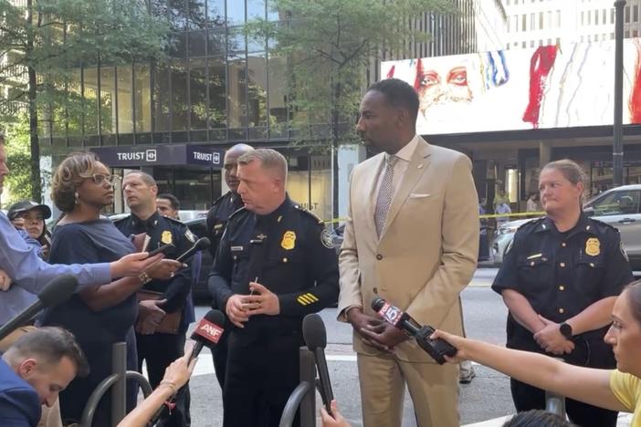 Atlanta Mayor Andre Dickens and police officials are shown speaking to reporters in downtown Atlanta.