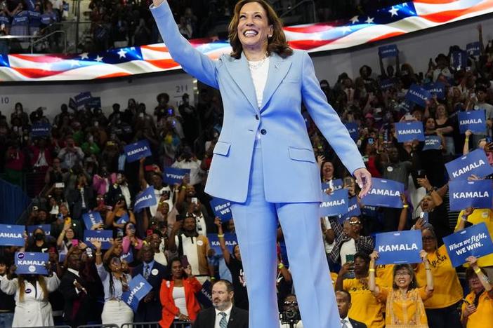 Kamala Harris is shown waving to a large crowd.
