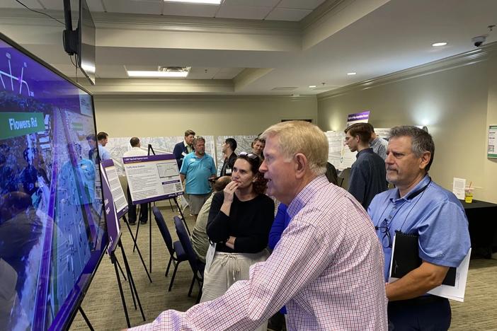 Attendees, including former Mayor Dennis Shortal (left) and Dunwoody Homeowners Association President Bob Fiscella watch a video that depicts the a visualization of the ai-285 Top End Express Lane in action. (Photo by Cathy Cobbs)