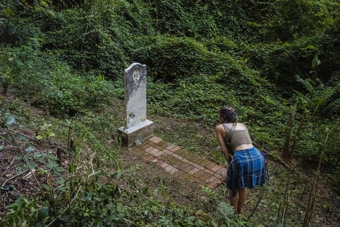 Participants in the recent tour of the Oak Ridge Cemetery in Macon explore the woods around the grave of Blanche Haywood. Until recent work by preservationists in the historically African American cemetery, the grave of the woman born in the 1840s  was completely hidden by the understory. 