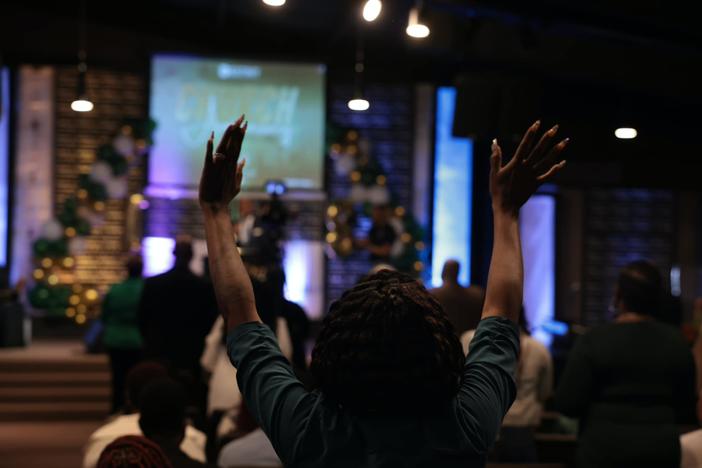 A woman raises her hands during church at Destiny Christian Center International.