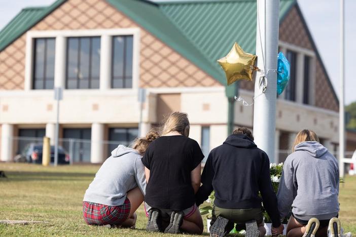 Students kneel before a makeshift memorial at Apalachee High School in Winder