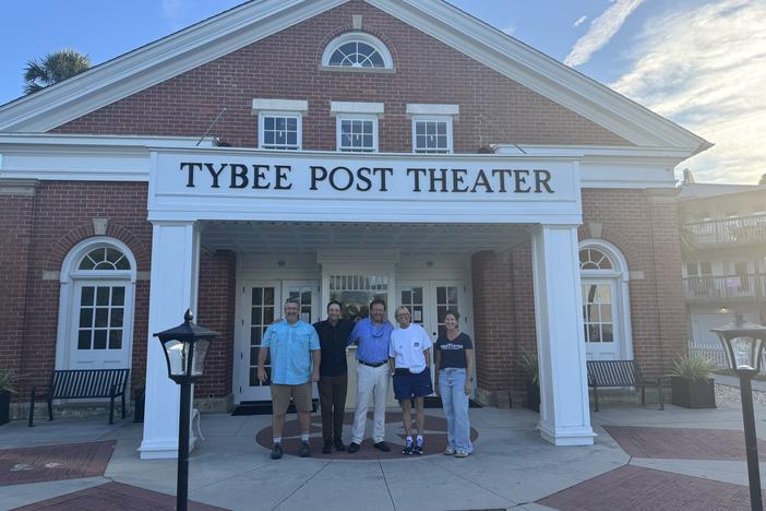 Five people standing in front of a brick building with a sign above them that says Tybee Post Theater