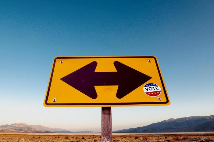 A road sign with a vote sticker on it.