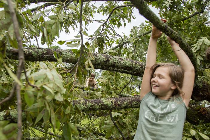 Aleah Martin, 8, right, and her cousin Riley Boyd, 12, play in the crown of a pecan tree blown down by Hurricane Helene in Aleah’s yard in Dublin, Ga.