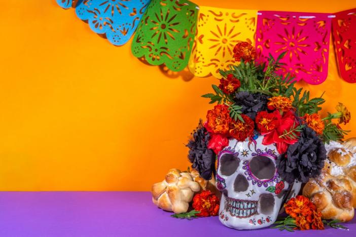 A skull sits prominently in front of an ofrenda, or Día de los Muertos offering table.