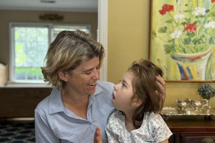 Mary Cota Reed holding her 8-year-old daughter Catherine in their Atlanta home. Ambria Burton/GPB News