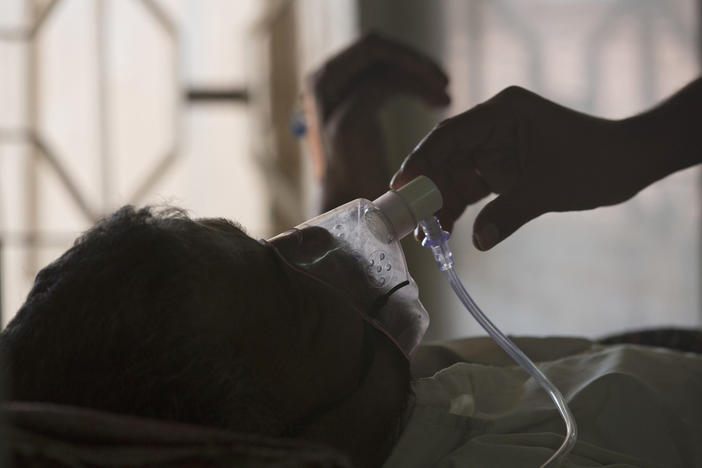 A relative adjusts the oxygen mask of a tuberculosis patient