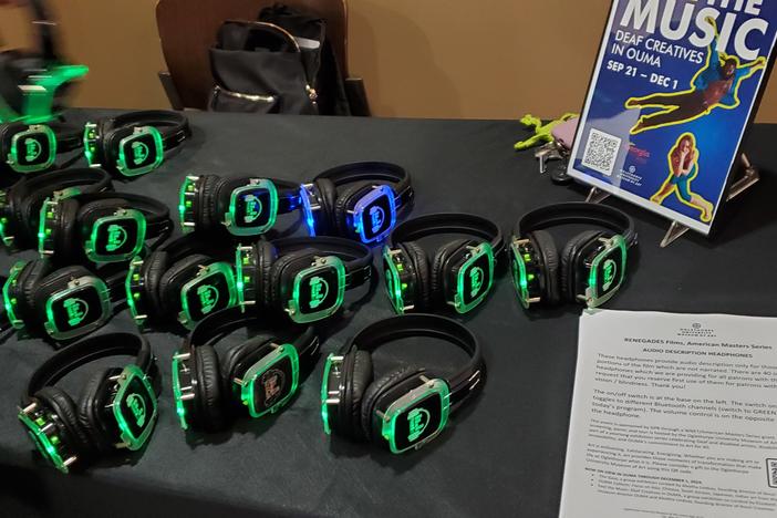 A table full of headphones that are lit on each ear with green LED lights